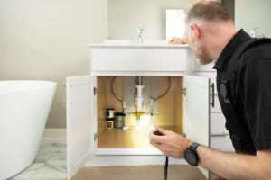 Inspector looking at plumbing under a sink.